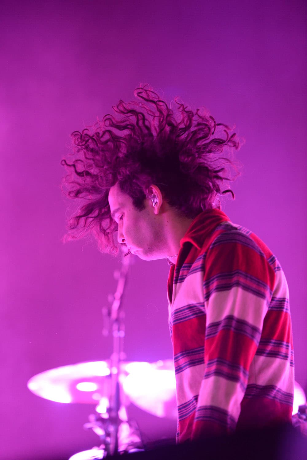 Concert photography of The 1975 frontman Matty Healy performing at Sprint Pavilion. Alternative rock band performance with dynamic stage lighting and professional concert venue documentation.