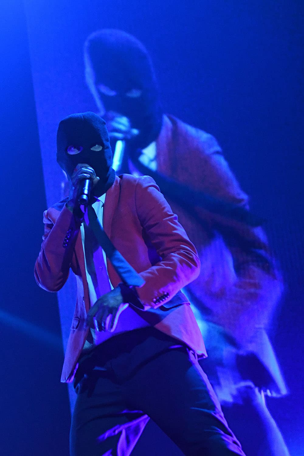 Concert photography of Tyler Joseph from Twenty-One Pilots performing on stage. Alternative hip-hop rock performance with dynamic stage presence and professional concert lighting capture.