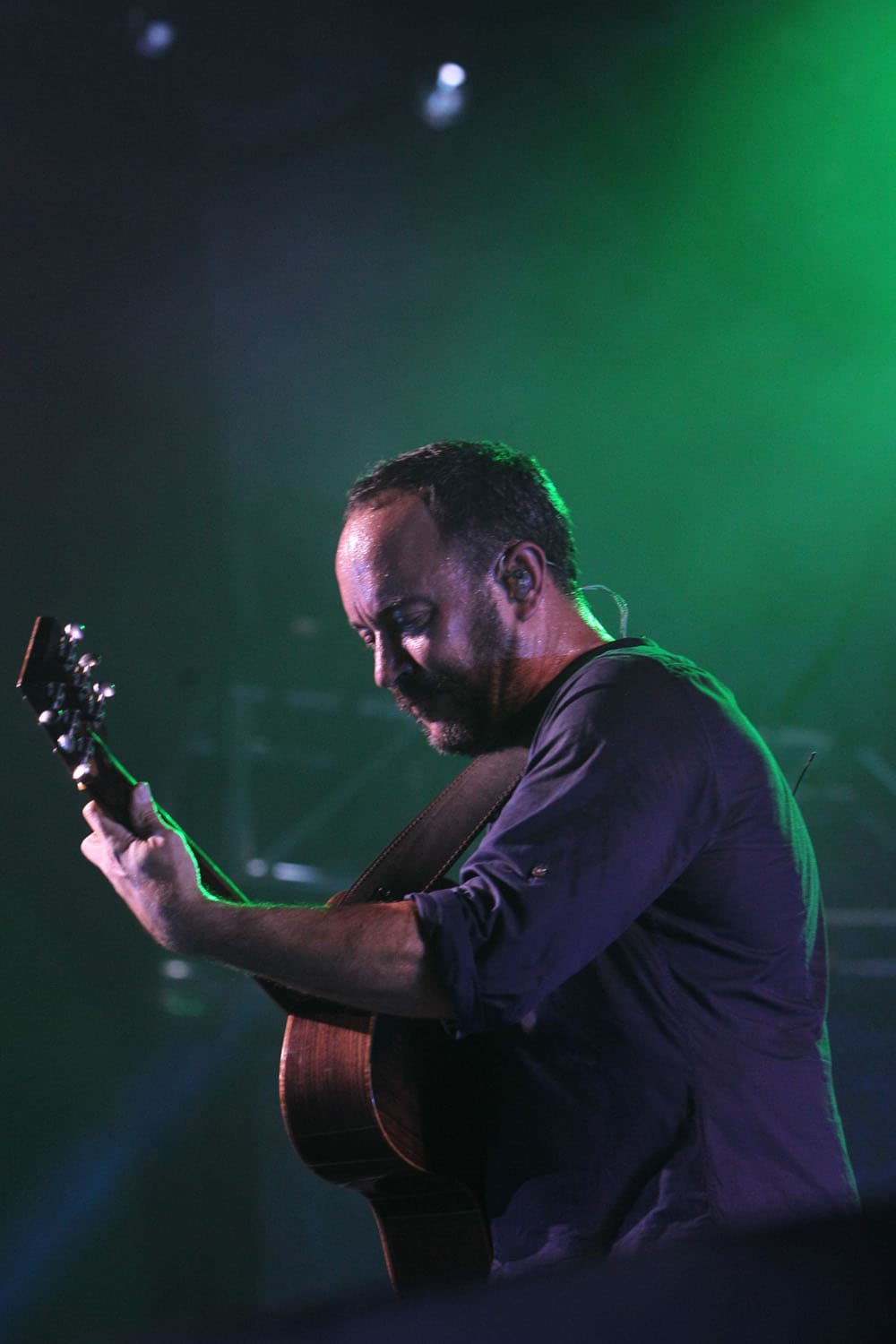 Concert photography of Dave Matthews Band frontman Dave Matthews performing. Jazz-funk rock performance with complex musicianship and large venue concert lighting expertly documented.