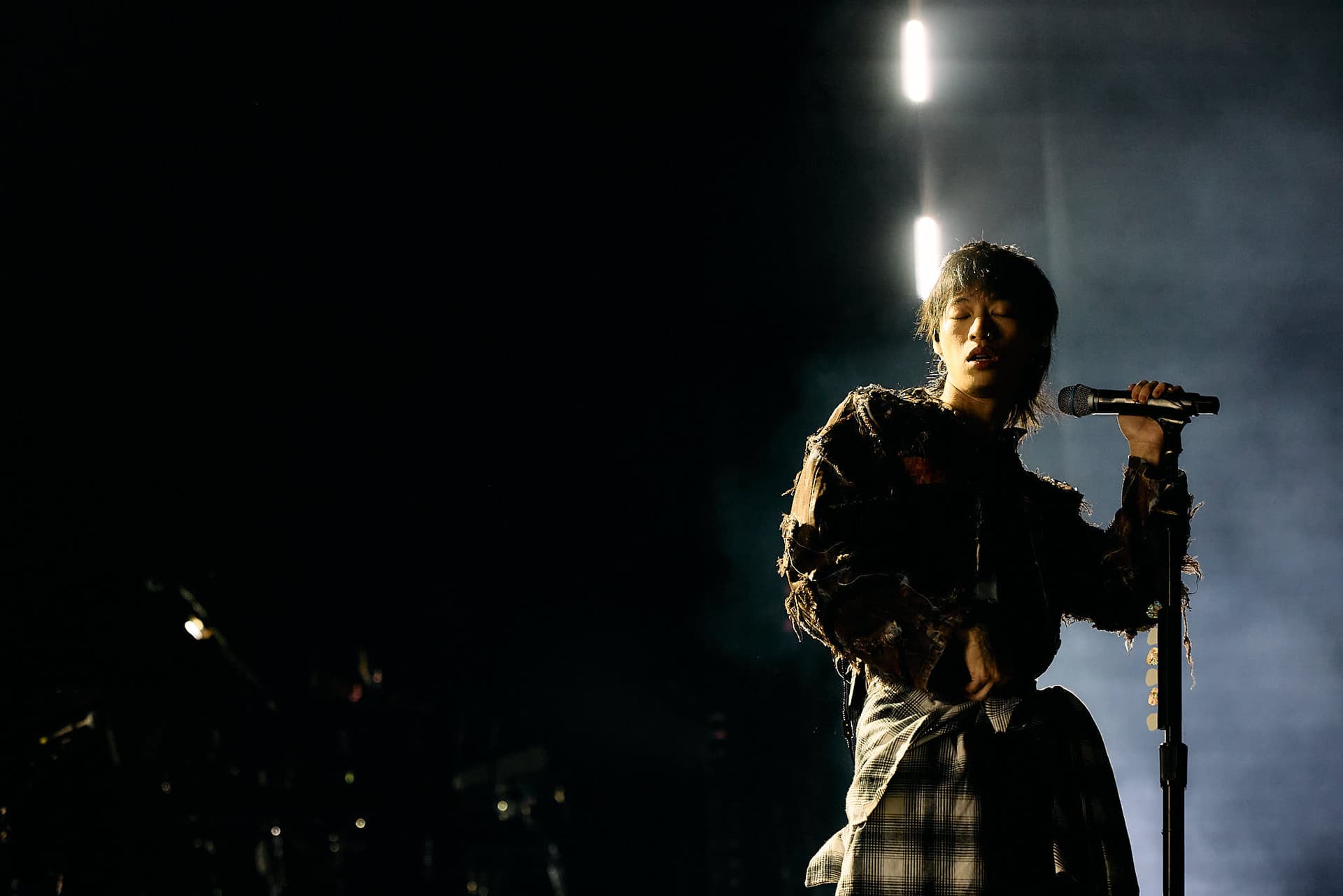 Concert photography of singer-songwriter Keshi performing on stage. Professional music performance photography demonstrating skill capturing intimate artist moments and stage lighting dynamics.