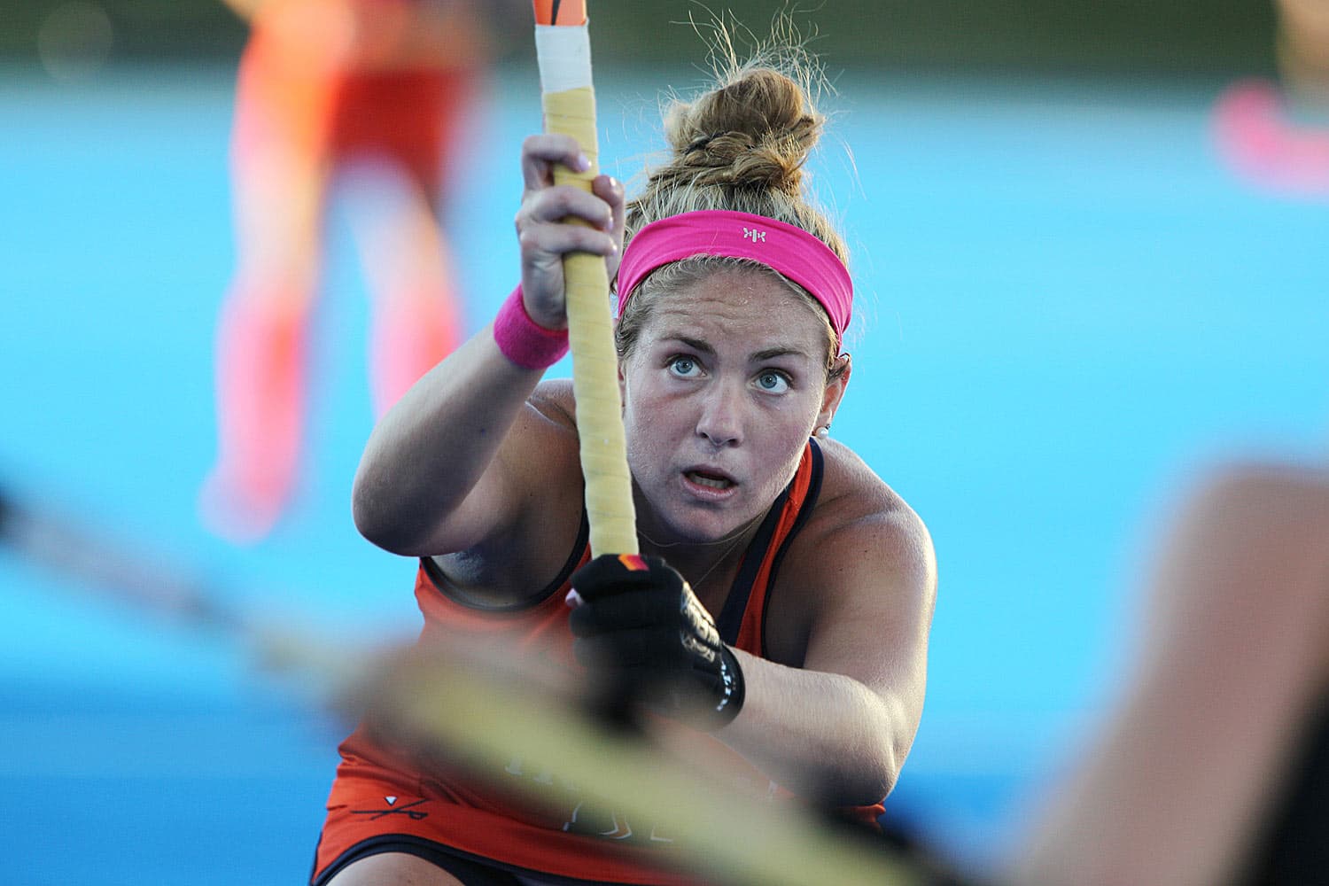 Erin Shanahan (#3) of the Virginia Cavaliers on the field for a match against Maryland in Charlottesville, VA, on October 17, 2017. Dressed in an orange uniform, she grips her field hockey stick, ready for action. The stadium lights illuminate the scene, highlighting the intensity of the competition.